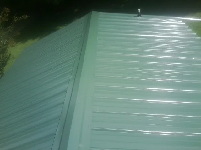 New green metal panels meeting at the ridge of a roof — Flat Roof Repair work by our crew in Buena Vista